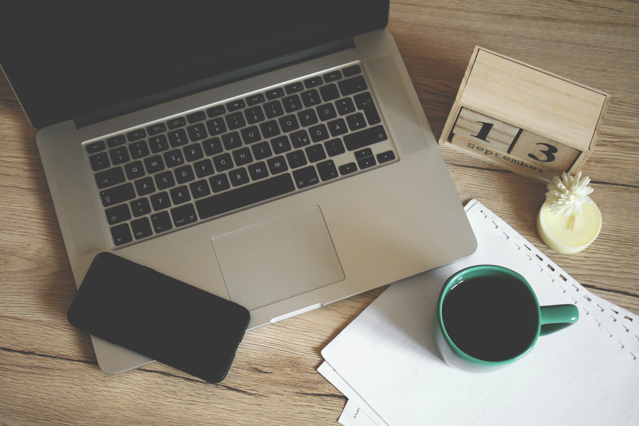 Desk with a laptop, coffee, phone, and papers on it. 