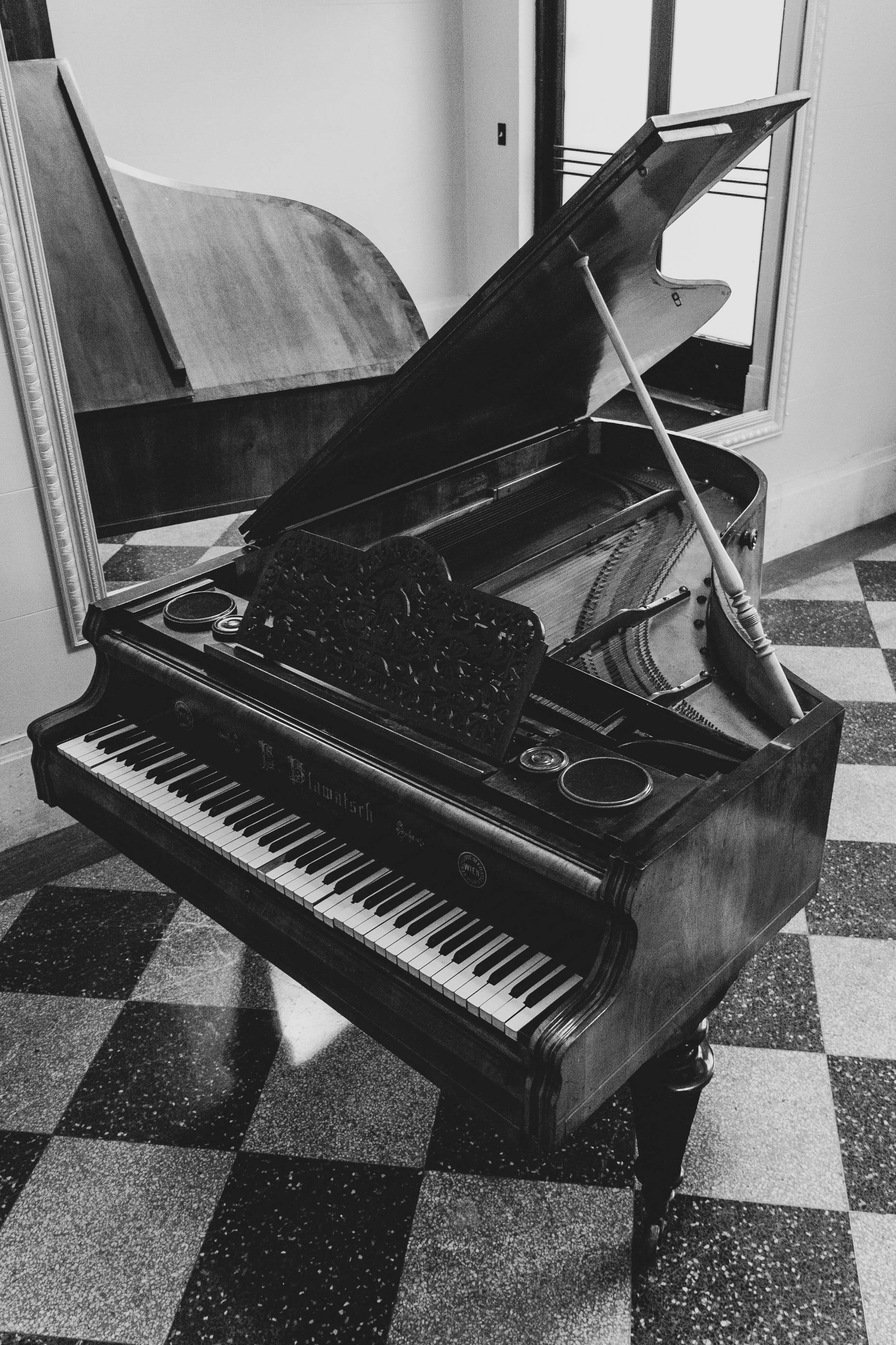 image of grand piano in room next to a mirror