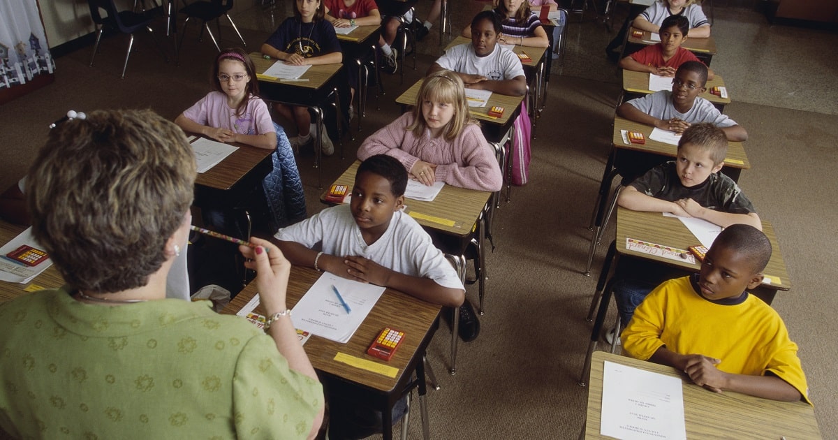 Diverse, young students sitting in a classroom looking at their instructor model something.